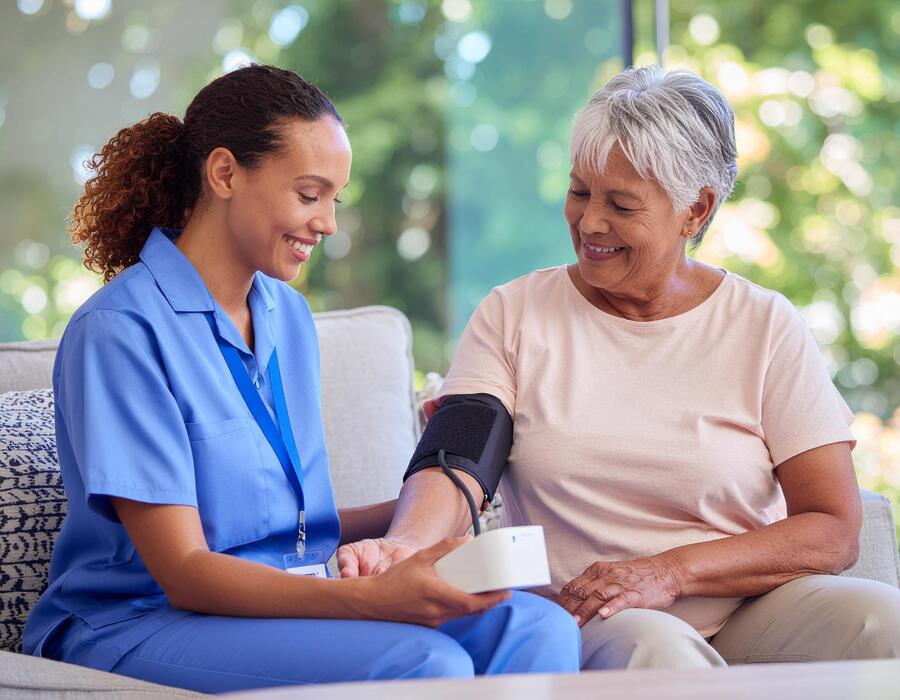 caregiver-assisting-an-older-adult-with-a-home-blood-pressure-check-on-a-sunny-afternoon-free-photo